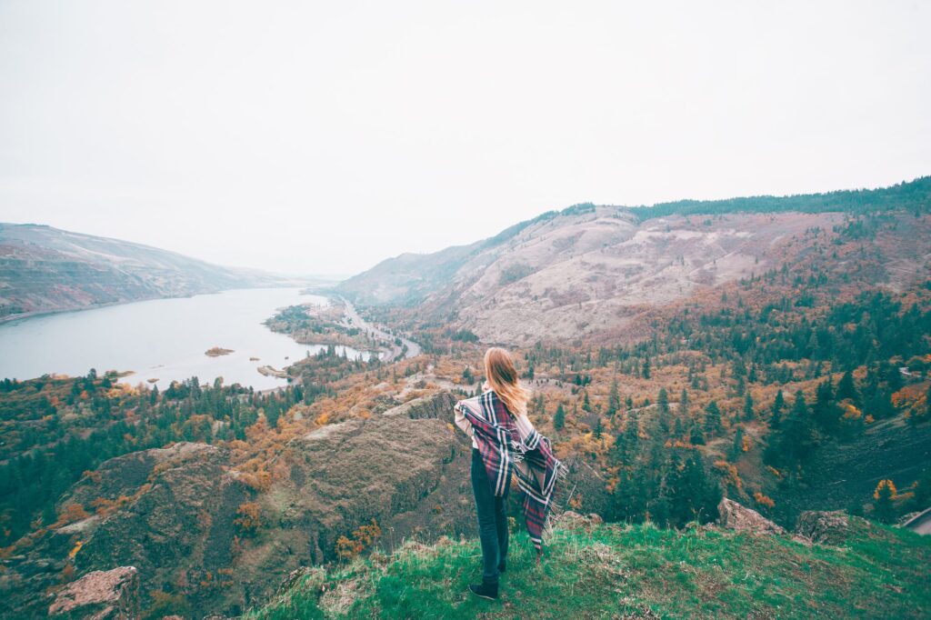 unrecognizable female tourist admiring lake in mountains